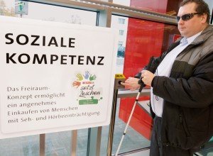Sehbeeinträchtigter Mann verwendet Unterstützungseinrichtungen in einer SPAR-Filiale
