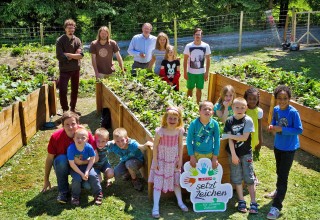 Kinder vor Blumenbeet. Gesundes Kinderdorf SPAR
