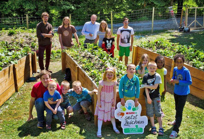 Kinder vor Blumenbeet. Gesundes Kinderdorf SPAR