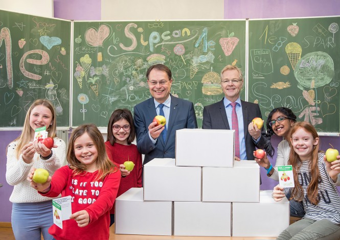 Schüler und Vorstandsvorsitzender Dr. Drexel mit gesunder Jause in Schulklasse vor Schultafel