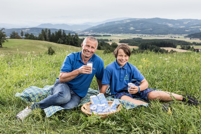 Franz Skuk und Sohn sitzen mit Milchprodukten in der Wiese
