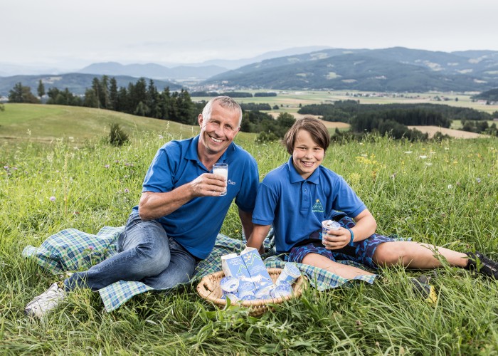 Jauntalmilch Franz Skuk und Sohn sitzen mit Milchprodukten in der Wiese