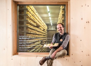 Michael Kerschbaumer  von Kaslabn sitzt mit selbst gemachtem Käse vor dem Reifelager