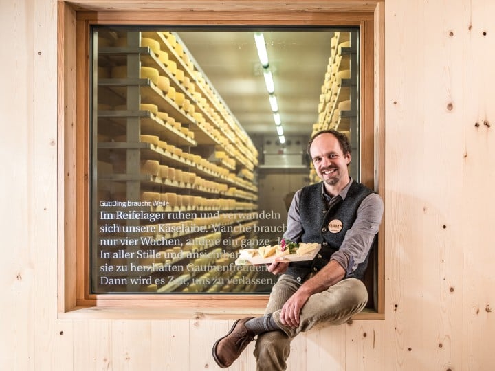 Michael Kerschbaumer  von Kaslabn sitzt mit selbst gemachtem Käse vor dem Reifelager