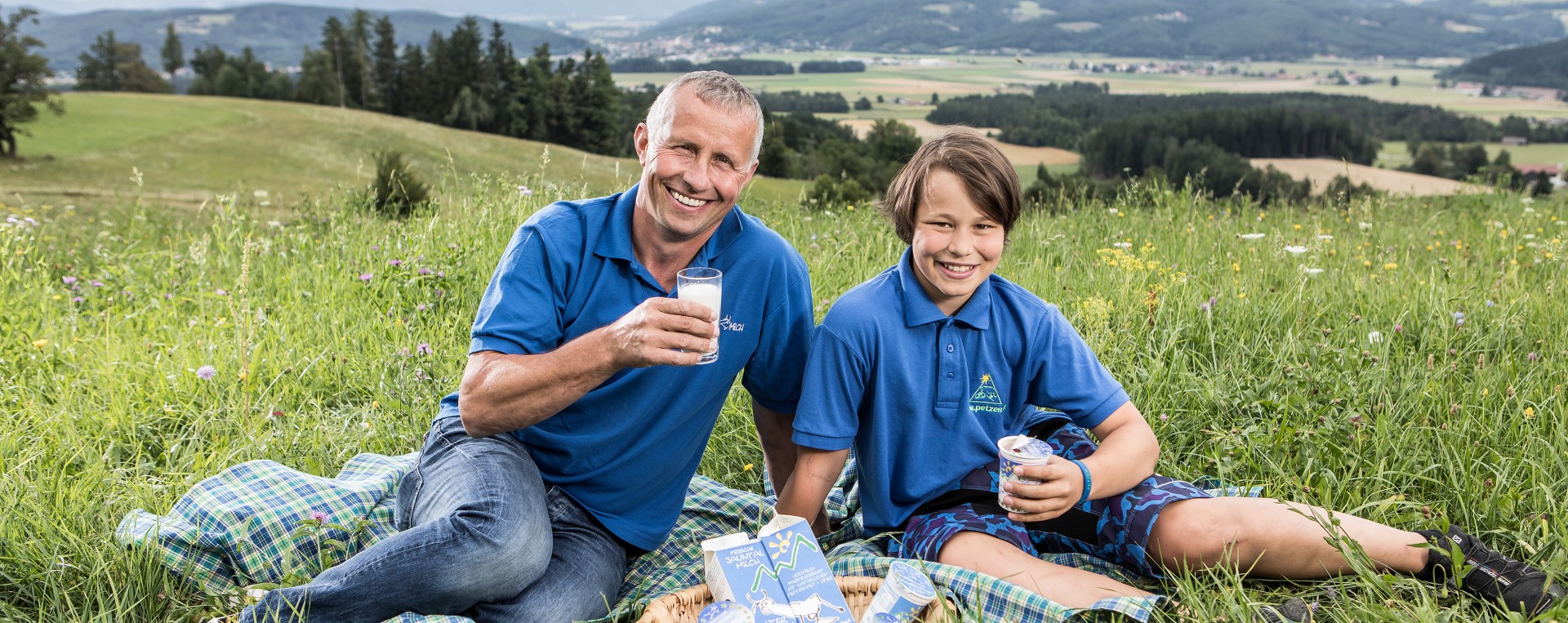 Jauntalmilch Franz Skuk und Sohn sitzen mit Milchprodukten in der Wiese