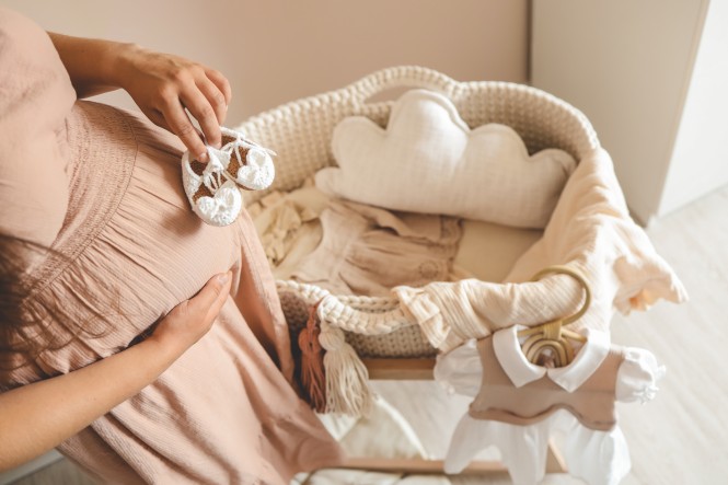 A pregnant woman holds cute baby shoes in her hands, the concept of expecting a baby.