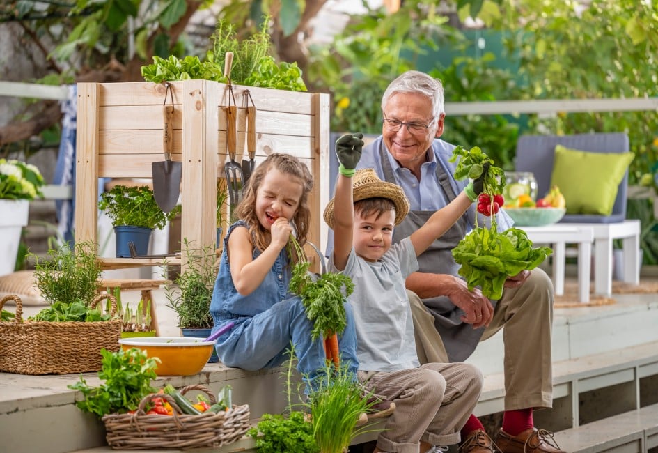 Ein Mann und zwei Kinder sitzen auf einer Treppe im Garten und halten ein Gemüse in der Hand