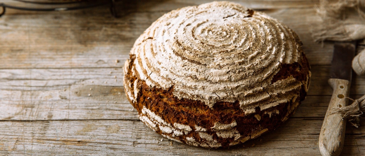 Ein knuspriges, rundes Sauerteigbrot auf einem Holztisch