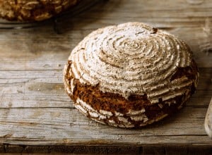 Ein knuspriges, rundes Sauerteigbrot auf einem Holztisch