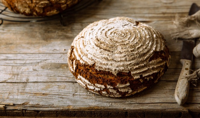 Ein knuspriges, rundes Sauerteigbrot auf einem Holztisch