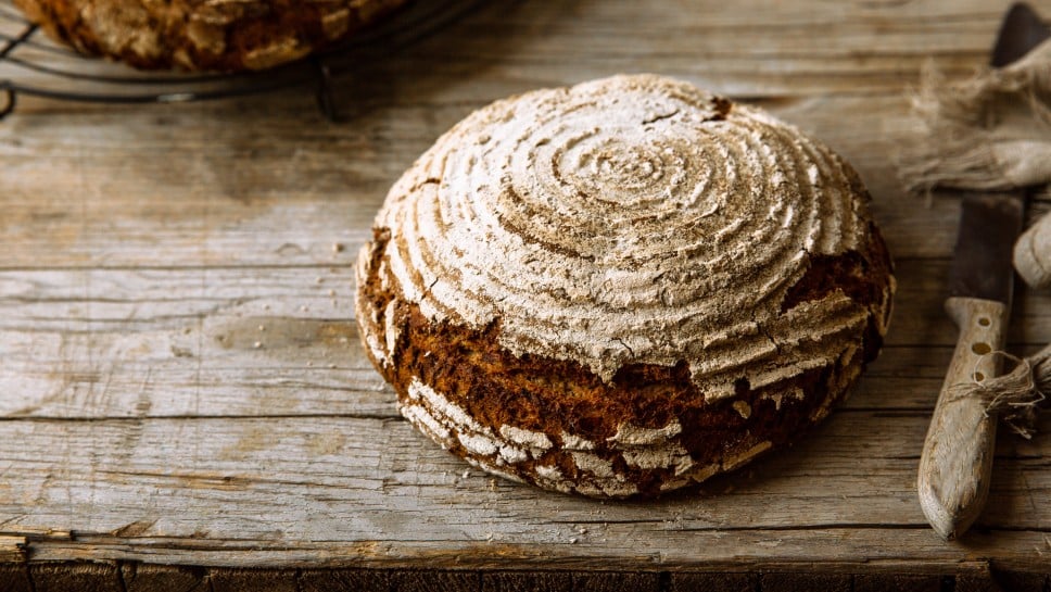 Ein knuspriges, rundes Sauerteigbrot auf einem Holztisch