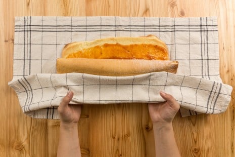 Die mit Marmelade bestrichene Roulade wird mit einem Geschirrtuch eingerollt