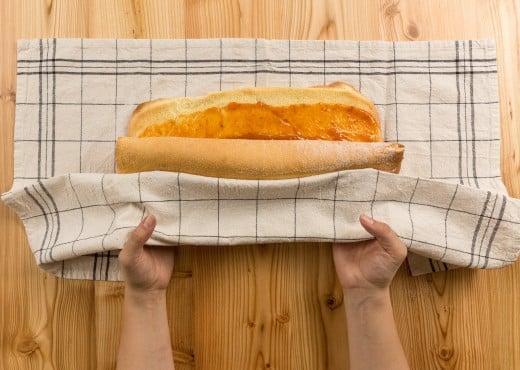 Die mit Marmelade bestrichene Roulade wird mit einem Geschirrtuch eingerollt