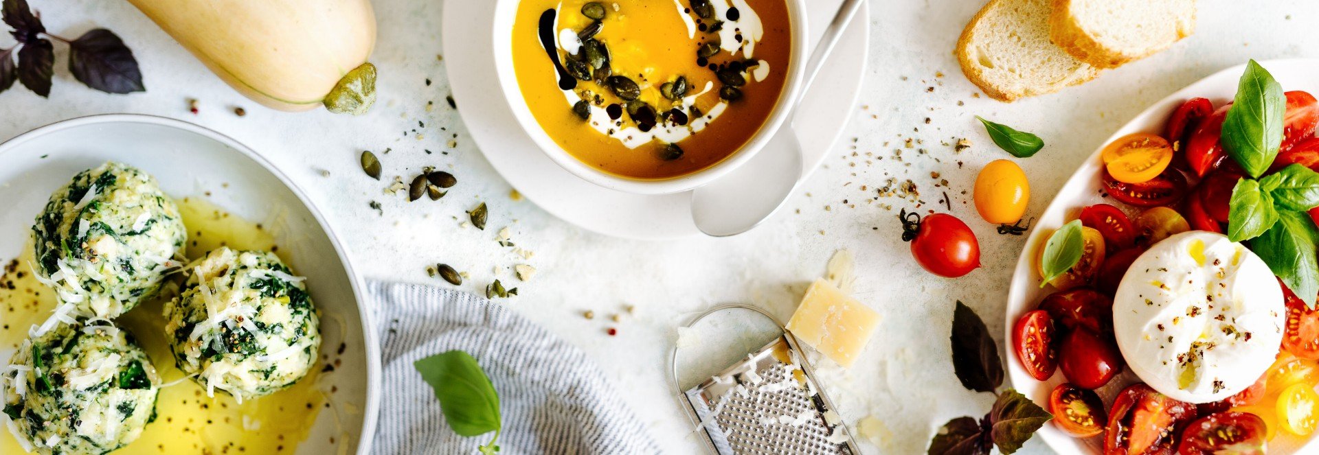 Beliebte vegetarische Rezepte Ein Tisch mit beliebten vegetarischen Gerichten: Spinatknödel, Kürbissuppe, Tomaten mit Burrata