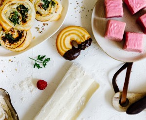 Ein Tisch mit beliebten Back-Rezepten: Topfentorte, Blätterteigschnecken, Brot und Punschkrapferl