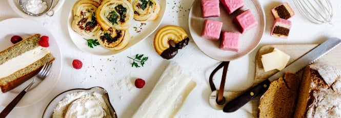 Ein Tisch mit beliebten Back-Rezepten: Topfentorte, Blätterteigschnecken, Brot und Punschkrapferl
