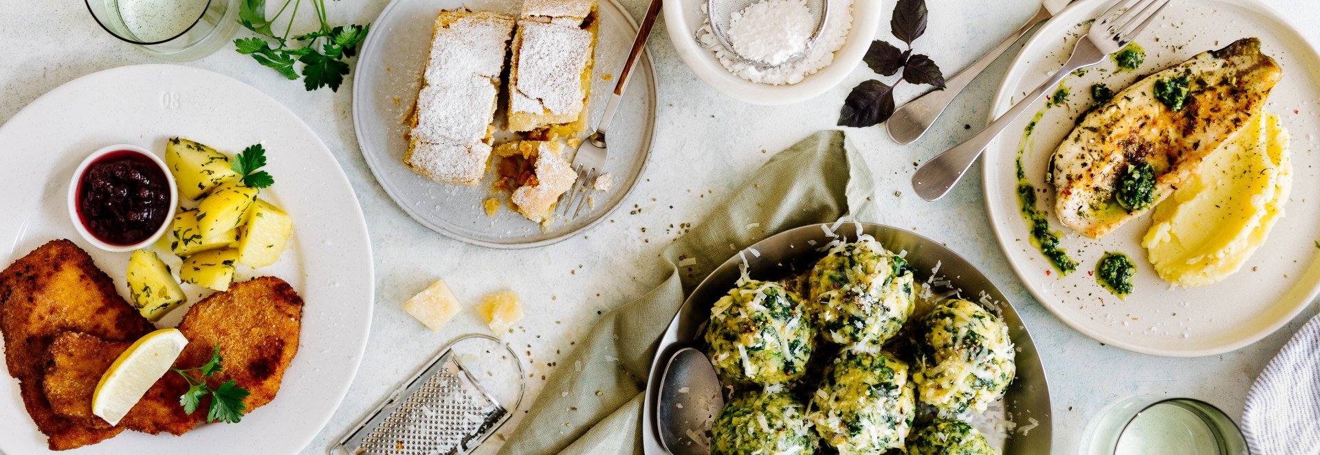 Ein Tisch mit beliebten Gerichten: Schnitzerl, Apfelschlangerl, Spinatknödel und Saibling mit Püree