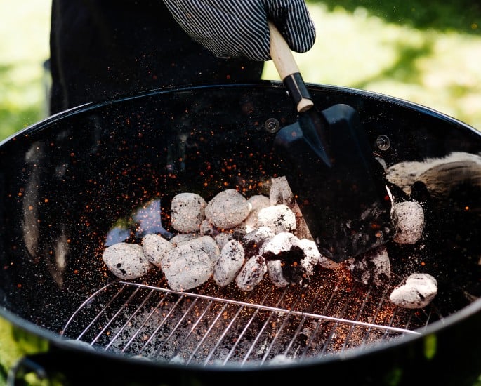 Griller wird mit Kohle angeheizt