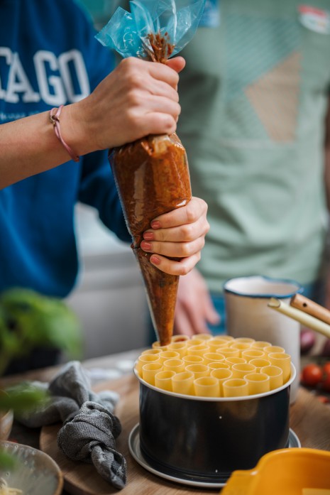 Tici füllt Tomatensugo in die Nudeln