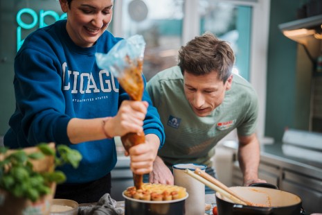Tici befüllt die Nudeln mit der Sauce und Hannes hilt ihr dabei