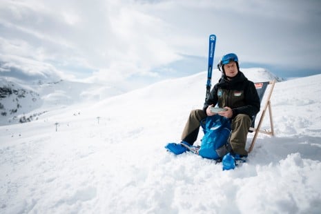 Skiass Hannes Reichelt sitzt im Liegestuhl im Schnee und genießt die Aussicht