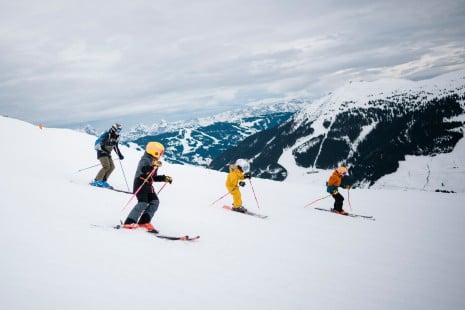 Skiass Hannes Reichelt wedelt mit Kindern auf der Skipiste 