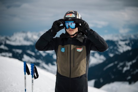 Skiass Hannes Reichelt steht im Schnee und setzt sich die Skibrille auf