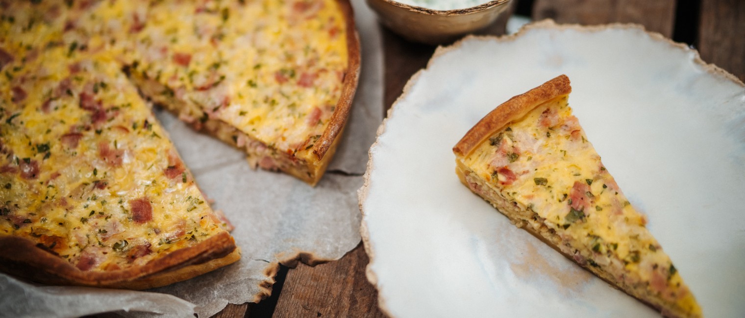 Ein Quiche Lorraine-Stück wird auf einem Teller serviert