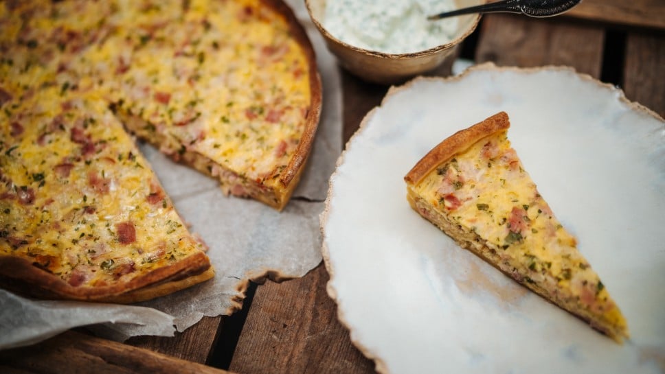 Ein Quiche Lorraine-Stück wird auf einem Teller serviert
