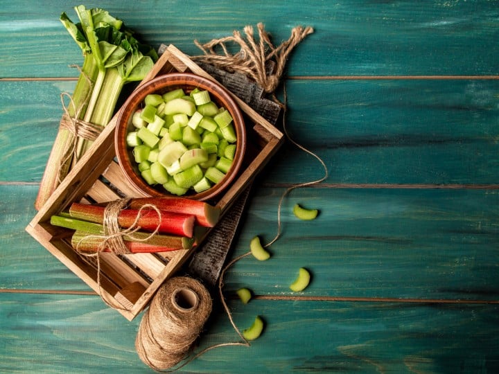 Rhubarb stalks on a board, Rhubarb in bowl on a wooden background. Rhubarb stalks on a board, Rhubarb in bowl on a wooden background. top view.