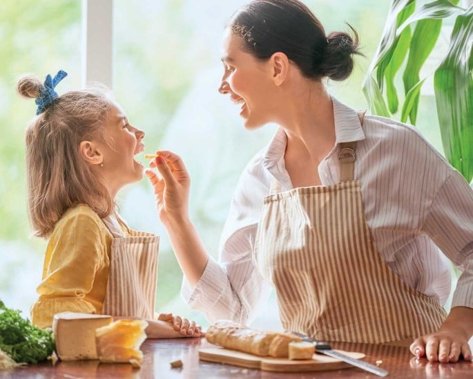 Mama und Kind kochen und mama lässt Kind etwas probieren