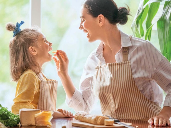 Mama und Kind kochen und mama lässt Kind etwas probieren