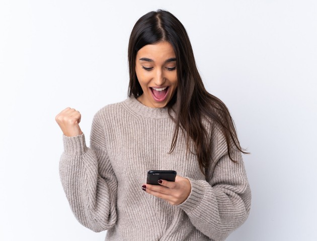 Frau schaut auf ihr Handy und freut sich
