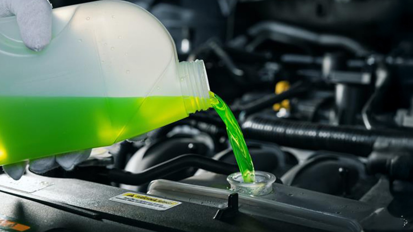 pouring antifreeze coolant liquid into car engine radiator 