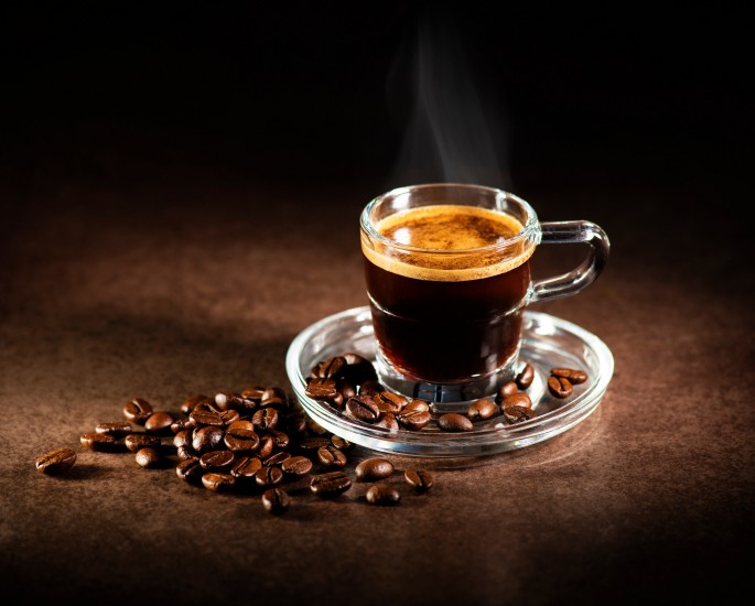 Espresso in einem transparantem Glas, Kaffeebohen daneben