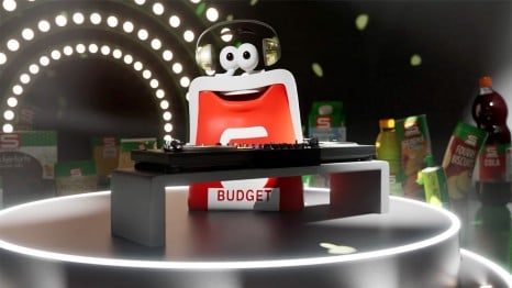 Das S-BUDGET Börserl mit Kopfhörer steht auf einer Bühne mit einem Dj-Pult umgeben von einigen S-BUDGET Produkten