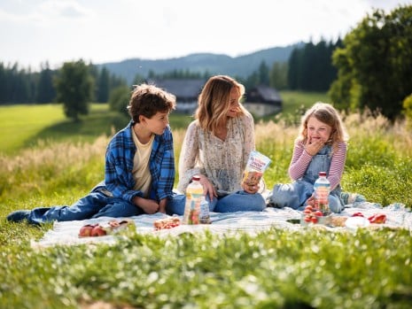 Marijam Weichselbraun macht mit zwei Kindern ein Picknick in der Natur und zusammen genießen sie SPAR Natur pur Produkte