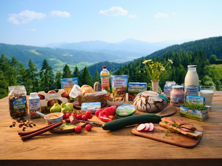 Bio-Produkte von SPAR Natur pur auf einem Holztisch; im Hintergrund eine schöne Berglandschaft