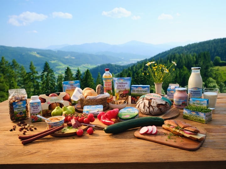 Bio-Produkte von SPAR Natur pur auf einem Holztisch; im Hintergrund eine schöne Berglandschaft