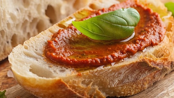 hier sieht man ein aufgeschnittenens Laib Weissbrot belegt mit Bruschetta al Pomodoro