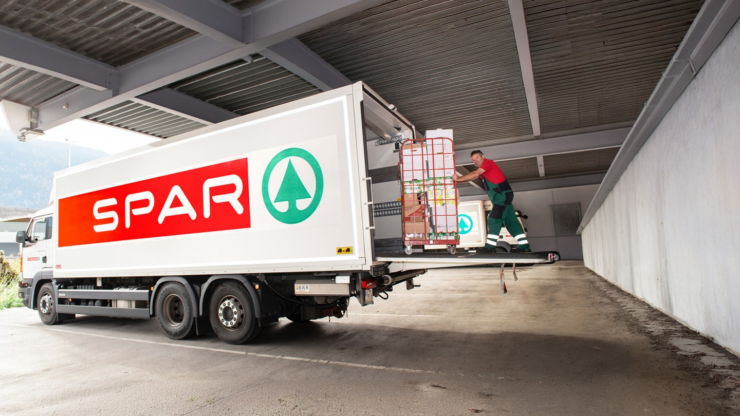 Mitarbeiter schiebt Wagen in einen SPAR LKW