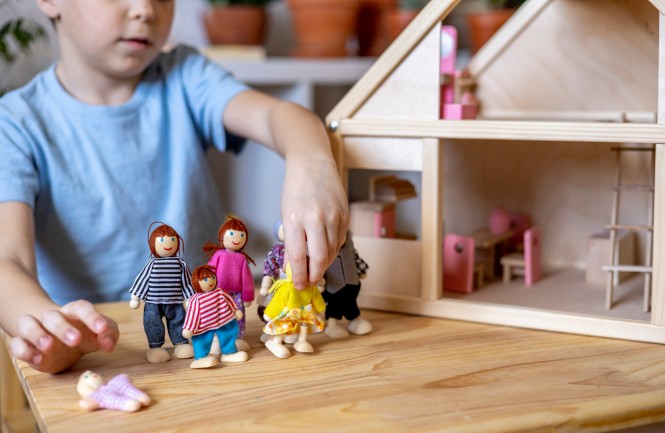 Montessori material. Toddler while playing with big pink dollhouse and having a great time. Gender confident little boy breaking stereotypes and socially imposed expectations.
