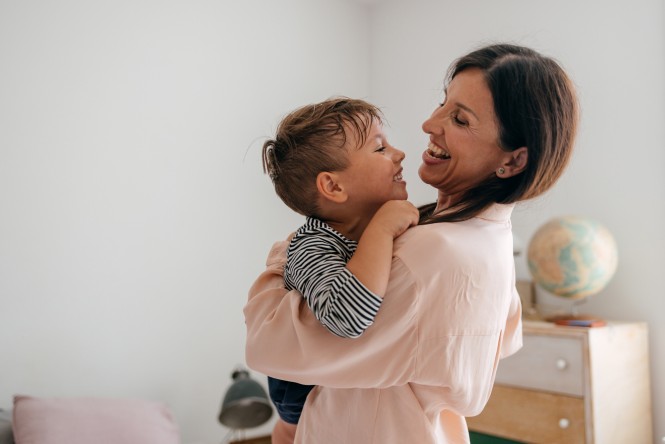A portrait of smiling mother and son in a warm embrace.