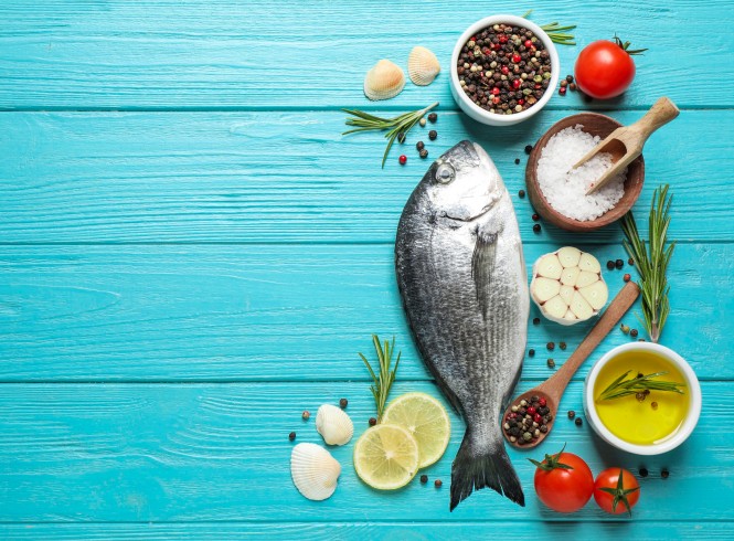 Flat lay composition with raw dorada fish on light blue wooden table, space for text