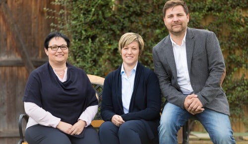 Familie Werkovits sitzend auf einer Bank im Hintergrund eine begrünte Scheune