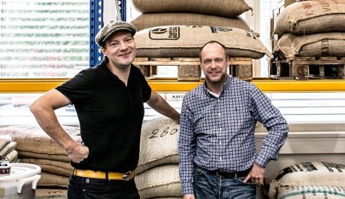 Oliver Goetz und Christian Schrödl vor einem Schwerlastregal mit geüfllt mit Kaffeesäcken