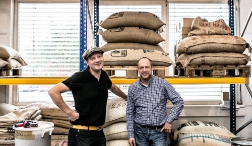 Oliver Goetz und Christian Schrödl vor einem Schwerlastregal mit geüfllt mit Kaffeesäcken
