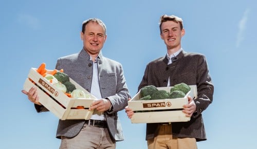 Franz und Florian Buchinger mit Holzkisten voll mit Gemüse auf einem Salatfeld