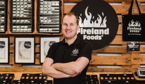 Richard Fohringer von Fireland Foos vor einem Regal aus Paletten mit verschiedenen Produkten des Unternehmens