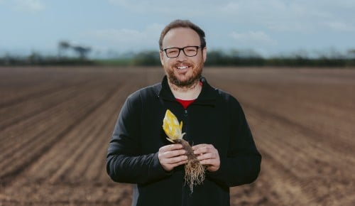 Martin Katinger mit Chicoree in den Hnden auf einem nicht bepflanzten Feld